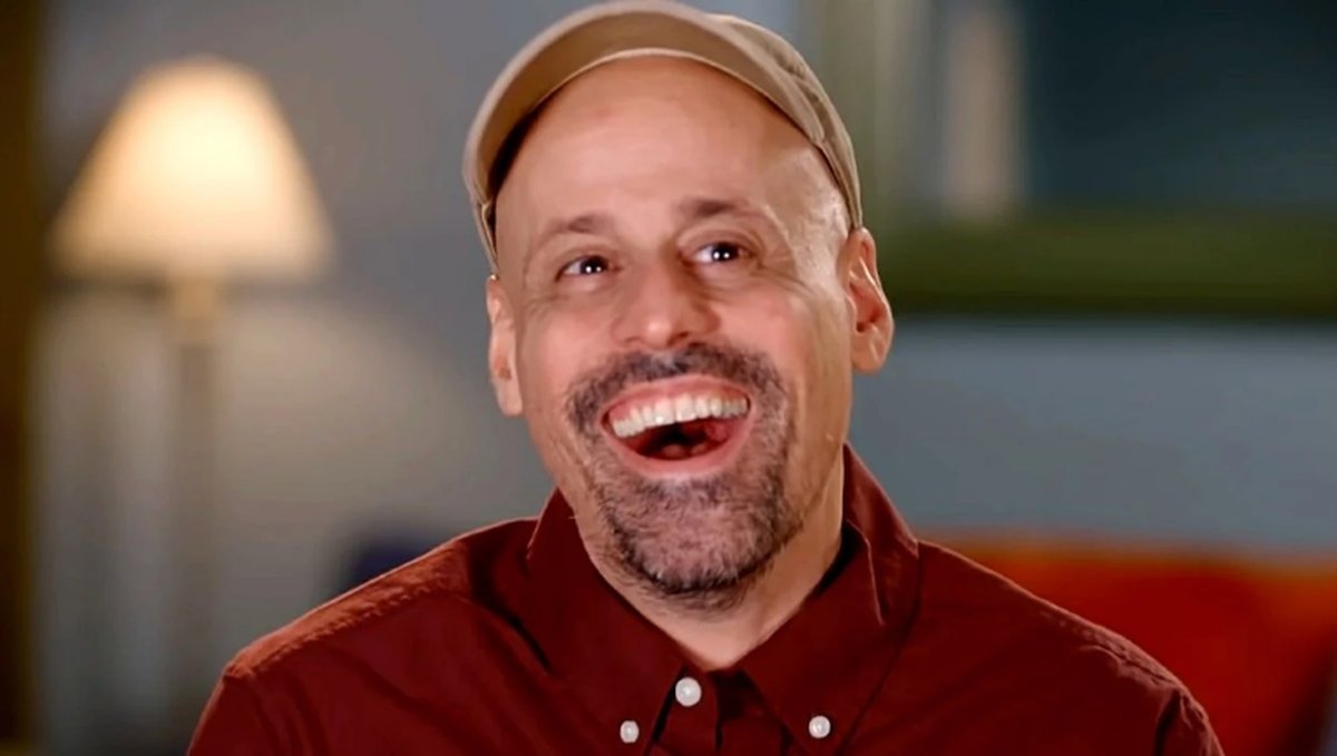 Gino Palazzolo laughing in a beige cap