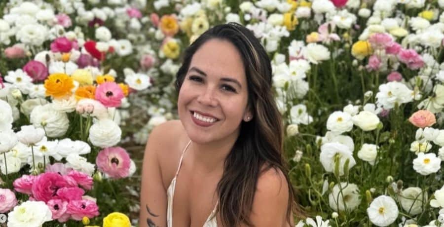 Liz Woods smiling with dark brunette hair among flowers