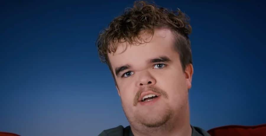 Jonah Johnston with curly hair in a confessional