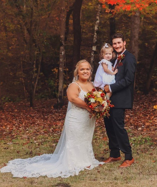 Liz Johnston in a white wedding dress with Brice Bolden holding Leighton