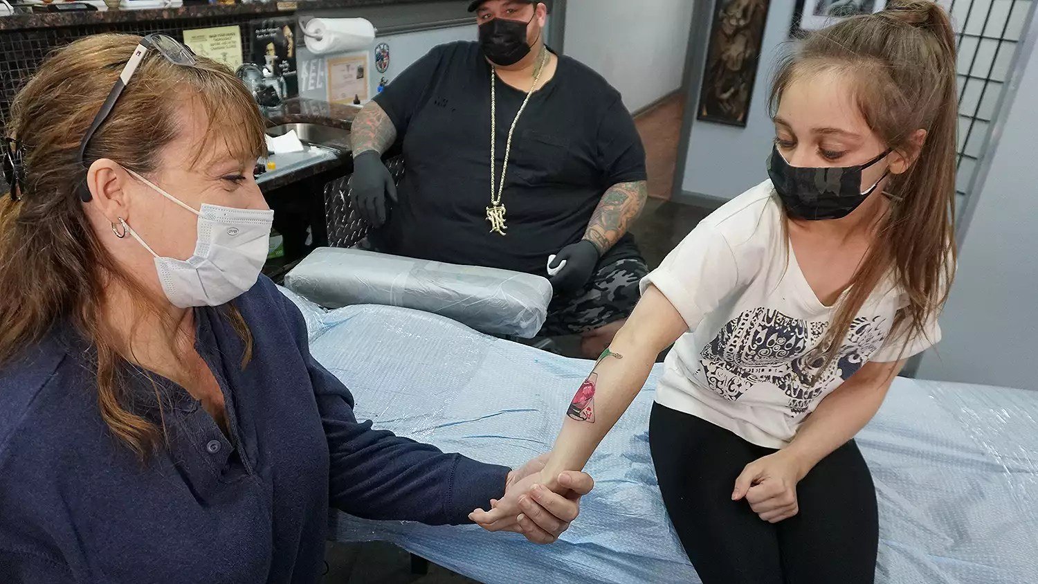 Shauna Rae showing a new arm tattoo at a tattoo shop with her mother