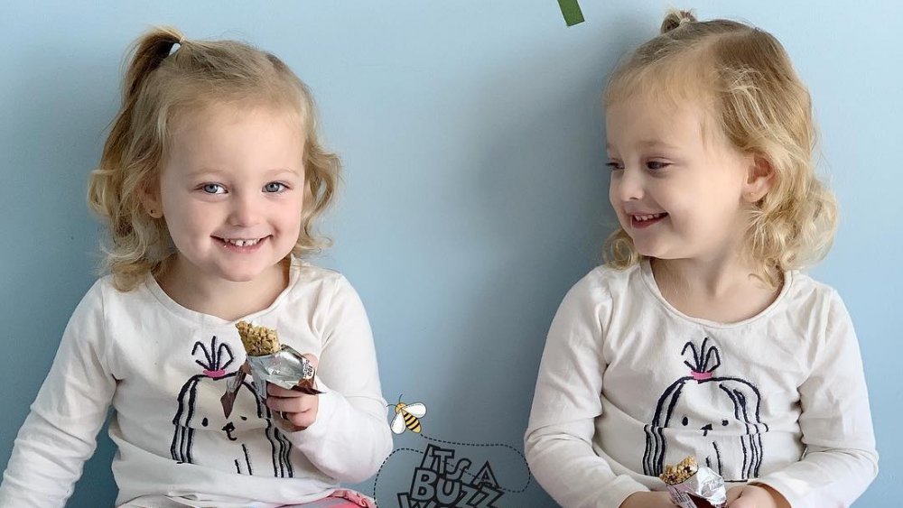 Ava and Olivia Busby side by side, showing the subtle differences Danielle uses to tell the identical twins apart