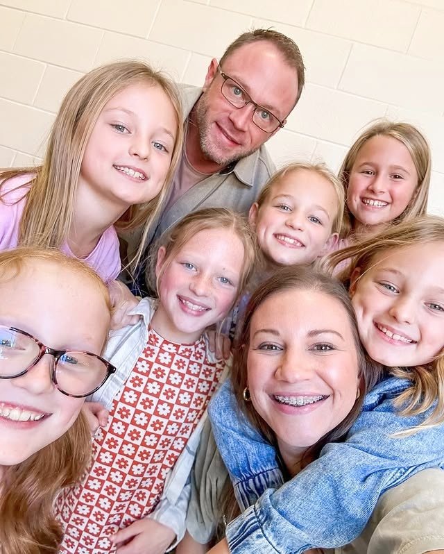 Adam and Danielle Busby with their six daughters smiling together