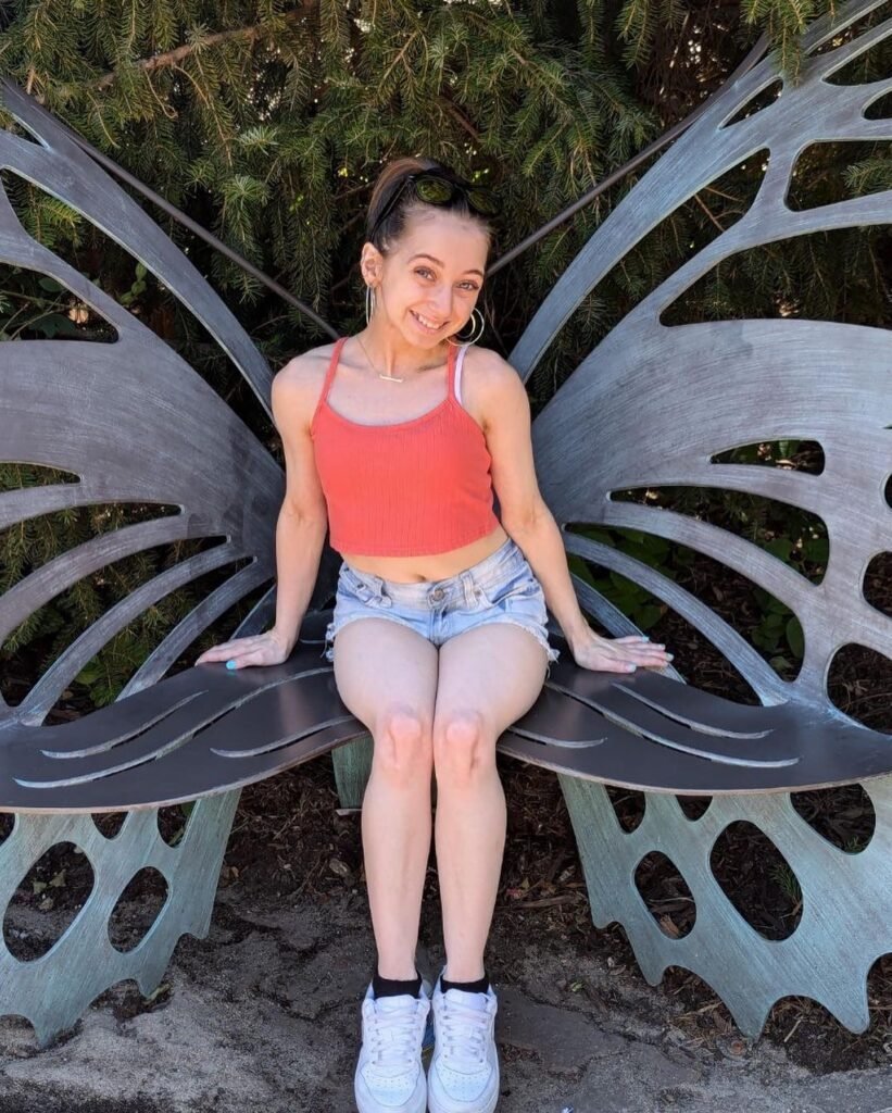 Shauna Rae posing confidently on a butterfly-wing bench