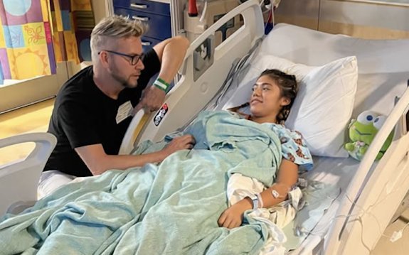 Kenny Niedermeier sitting beside daughter Hannah's hospital bed