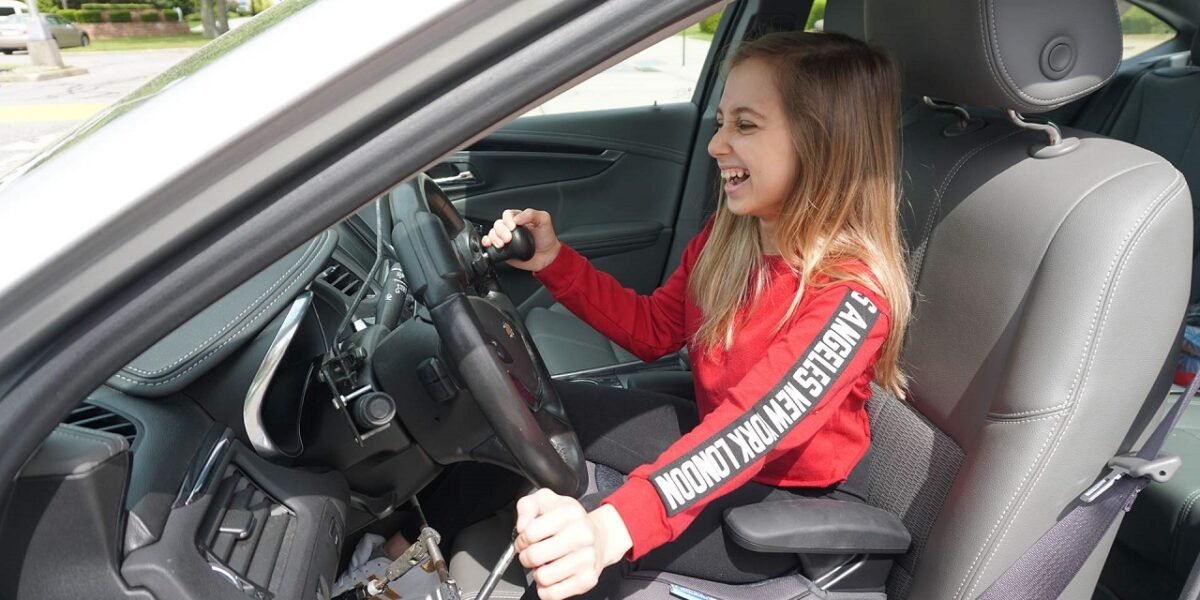 Shauna Rae smiling while driving a car with hand controls