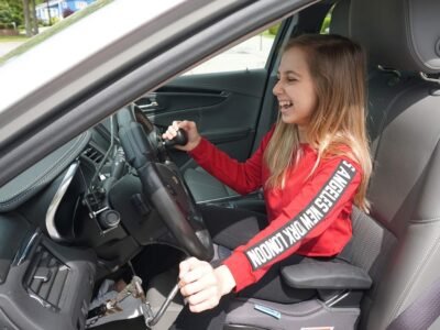 Shauna Rae smiling while driving a car with hand controls