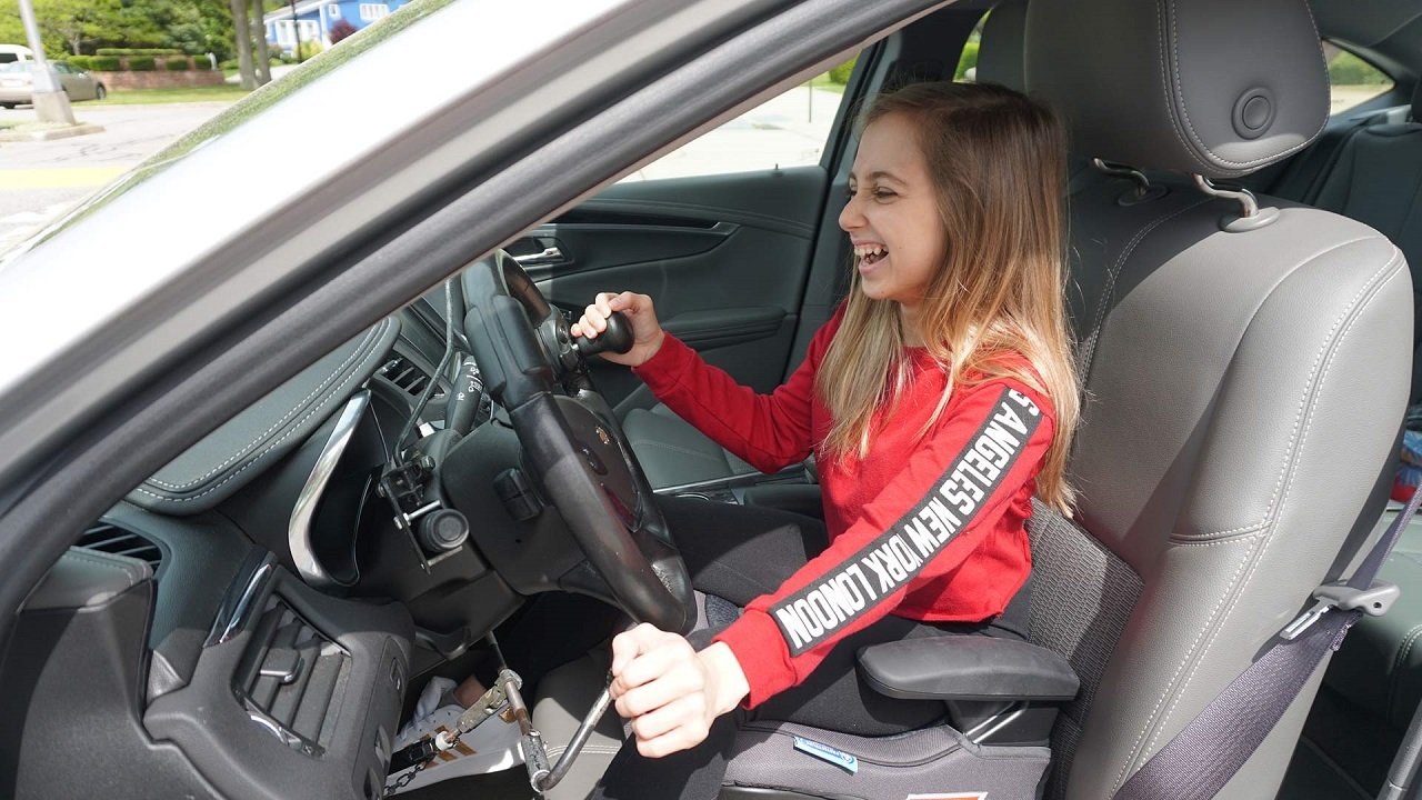 Shauna Rae smiling while driving a car with hand controls