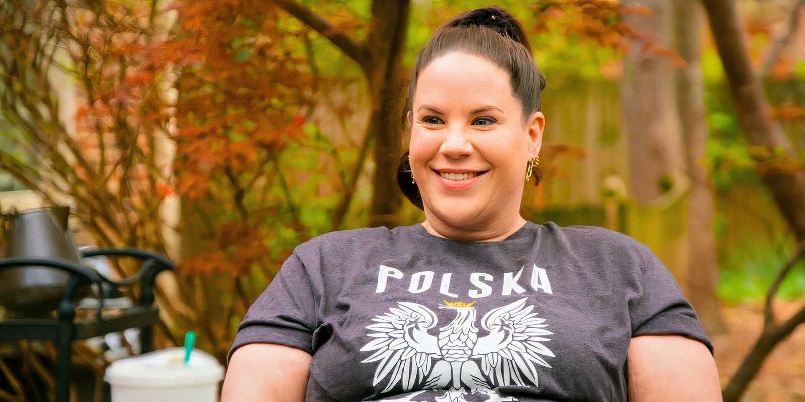 Whitney Way Thore smiling outdoors in a gray t-shirt