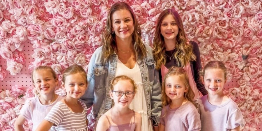 Danielle Busby with Blayke and the quintuplets in front of a pink flower wall