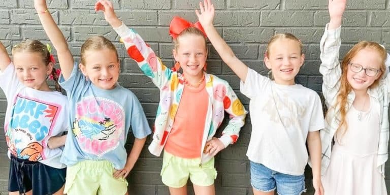 The Busby quintuplets raising their hands against a brick wall