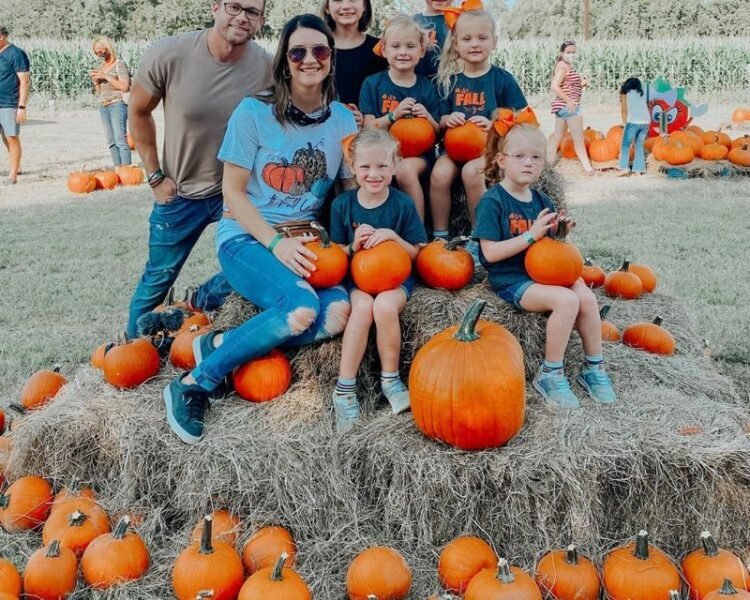 Adam and Danielle Busby with Blayke and the five quints at a pumpkin patch holding pumpkins