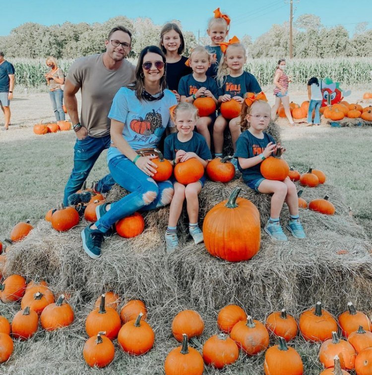 Adam and Danielle Busby with Blayke and the five quints at a pumpkin patch holding pumpkins