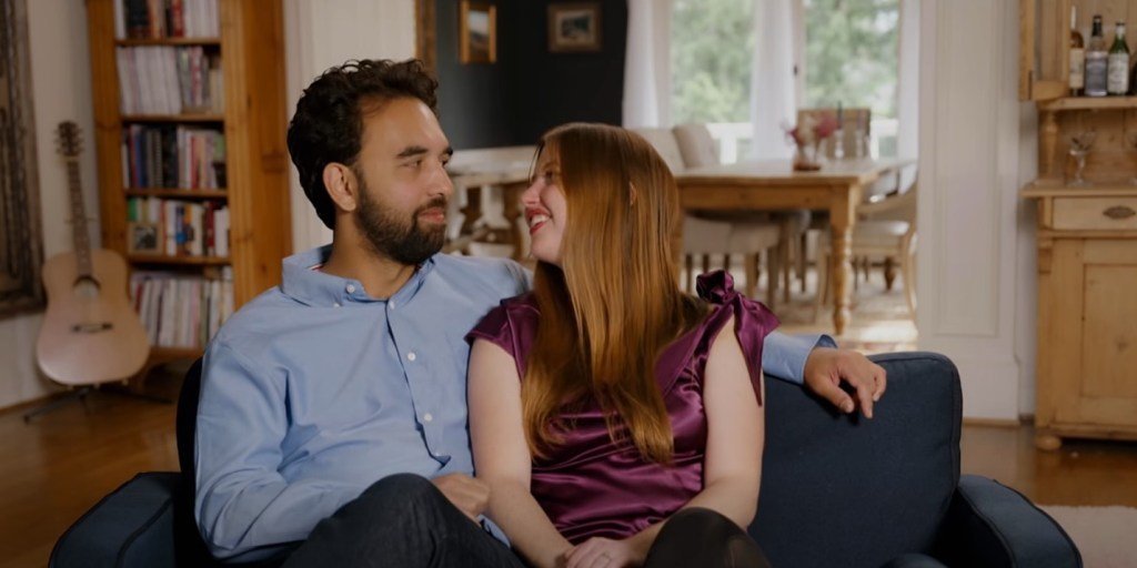 Catie Norboe and Josh Atkins sitting together on a sofa on 90 Day Fiance