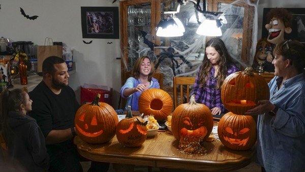 The Schrankel family carving Halloween pumpkins around a table